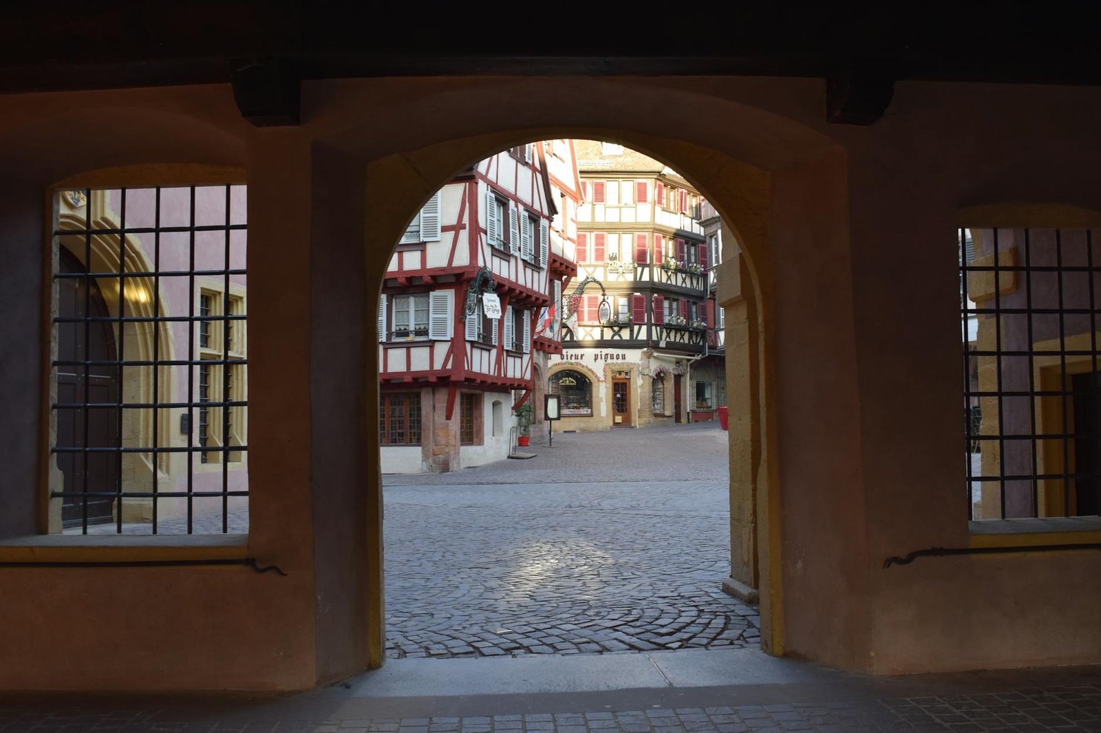 Scenic view through archway showcasing traditional Alsatian buildings in Colmar, France.