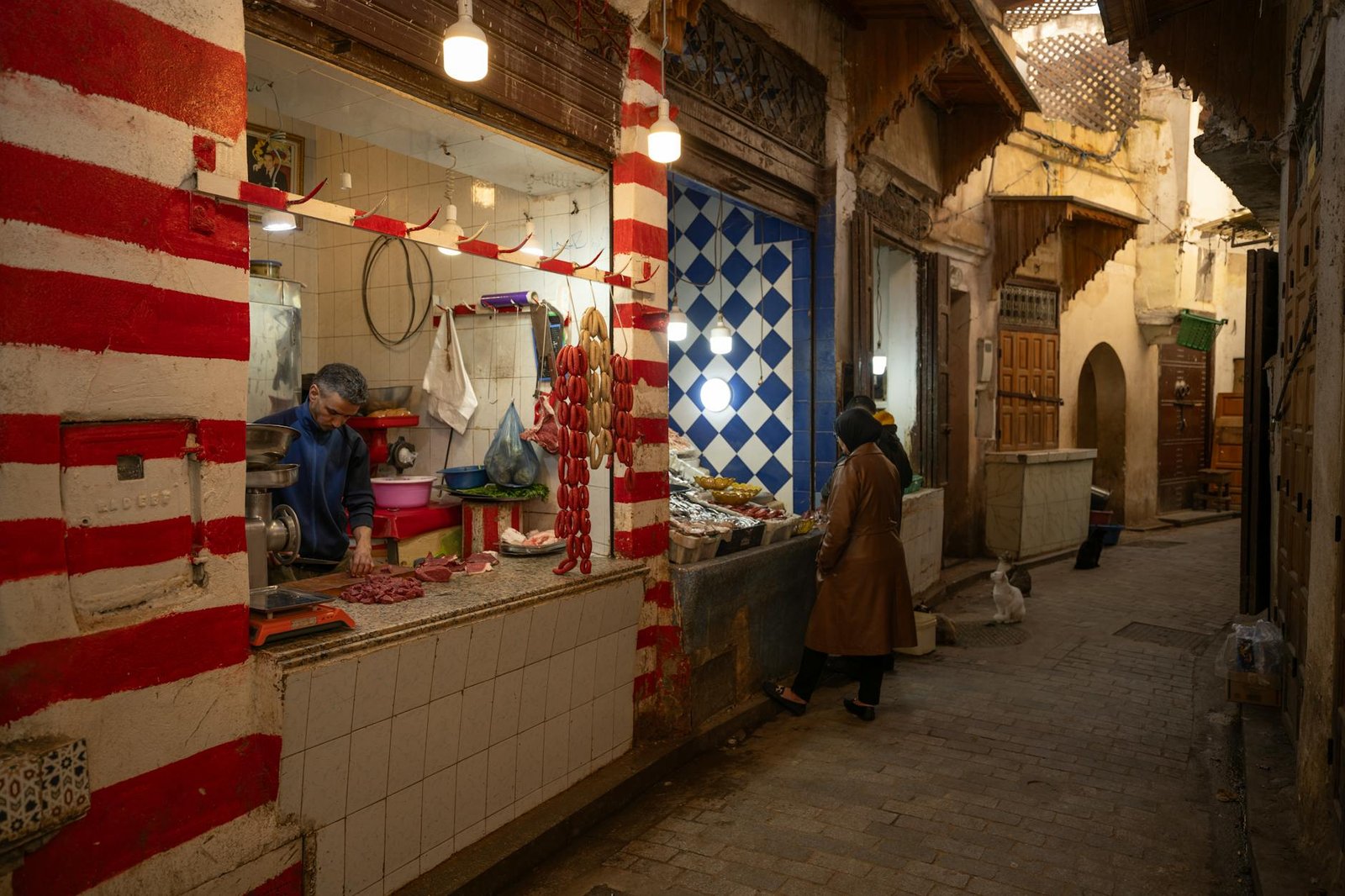 Explore the lively night scene of a traditional market in Fez, Morocco, with vivid colors and local charm.