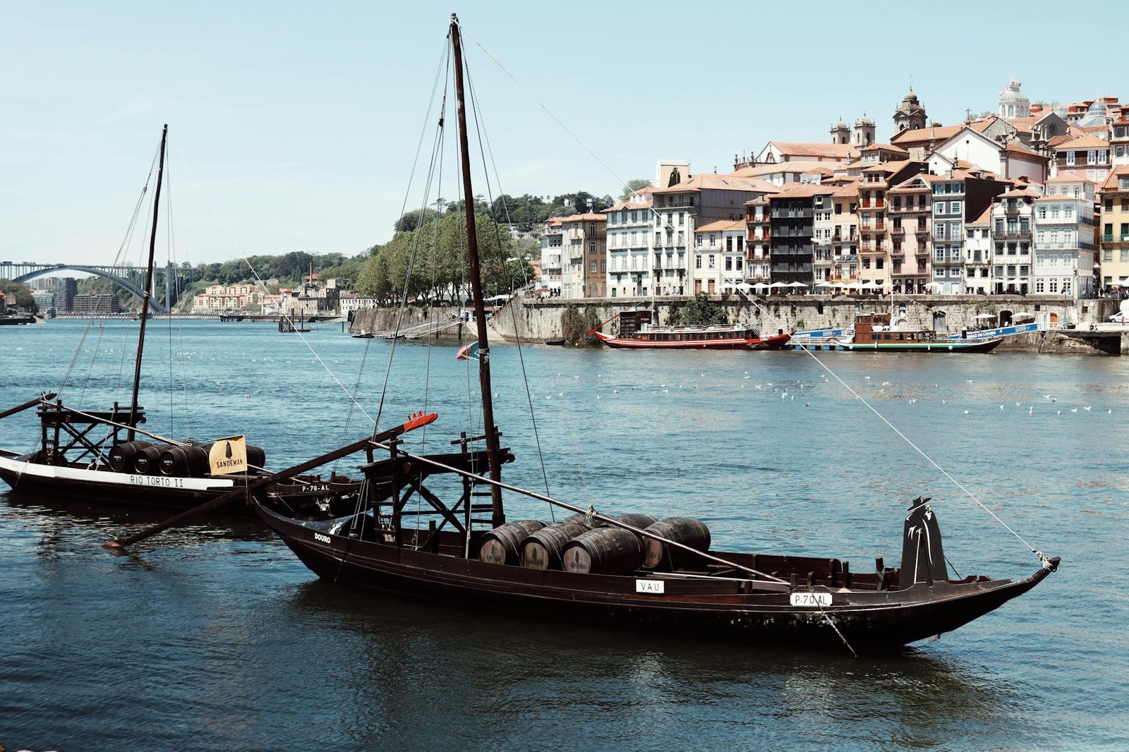 A scenic view of traditional fishing boats on the Douro River in Porto, Portugal, with historic architecture.
