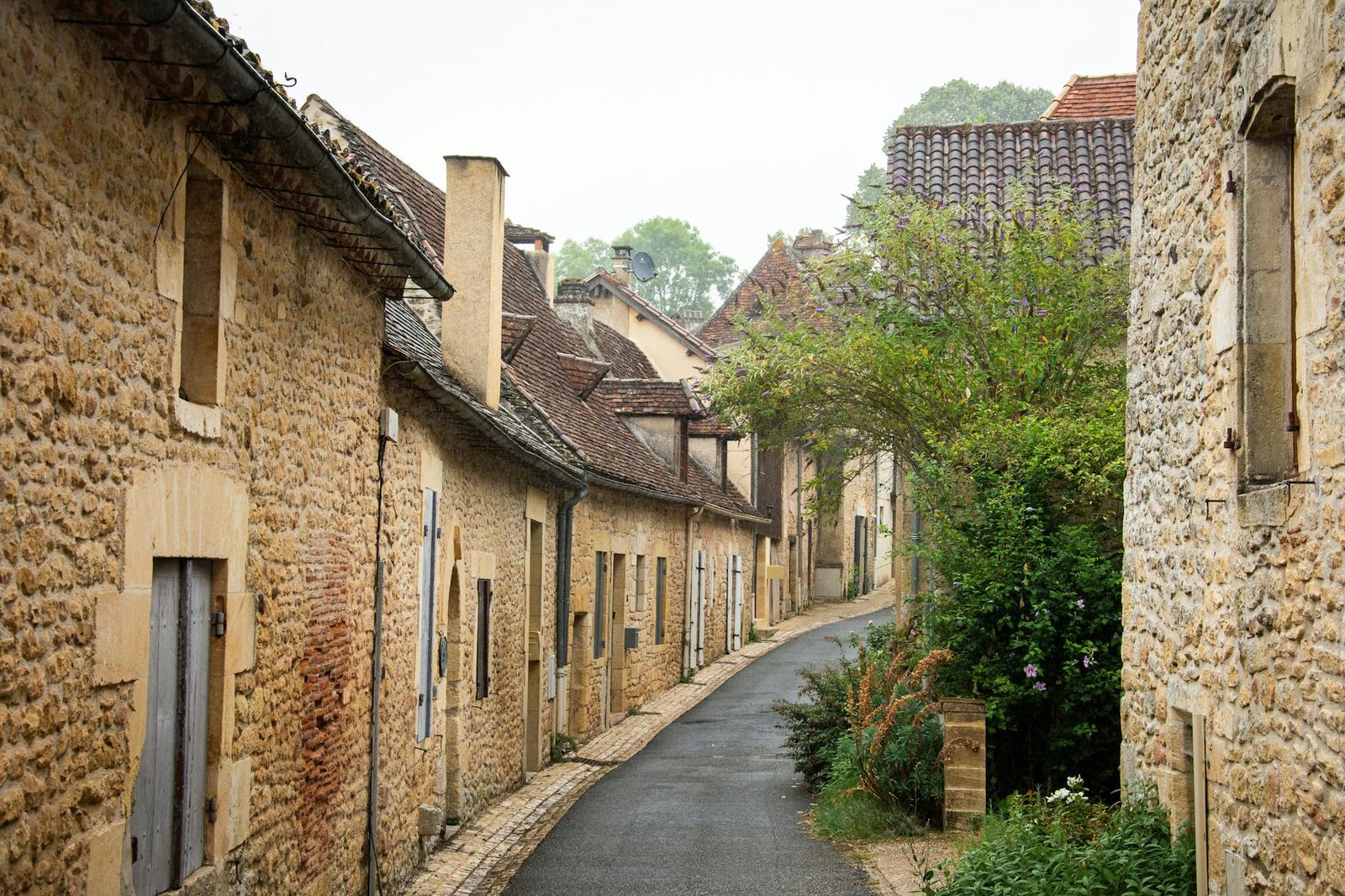 Picturesque narrow street with stone houses in a quaint French village, perfect for travel enthusiasts.