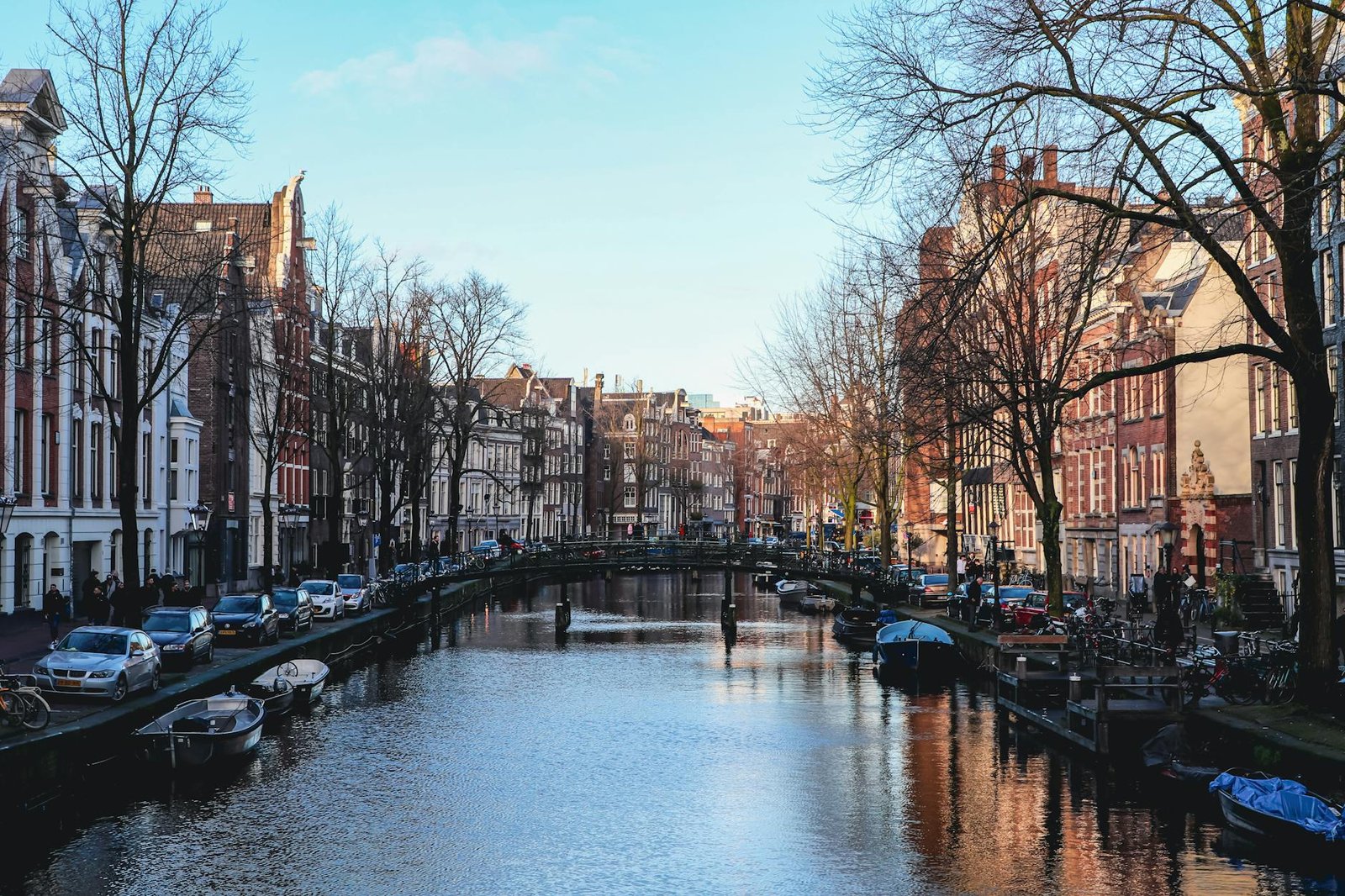 Scenic view of an Amsterdam canal lined with historic buildings, boats, and a tranquil atmosphere.